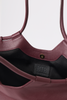 [color: merlot leather] Close-up of a burgundy leather shoulder bag with a black fabric lining and a black BTB London logo patch on the inside.