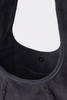 [color: navy suede] Close-up of a dark gray suede shoulder bag showing the interior lining, a side pocket with a snap button, and braided fringe detail along the bottom edge.