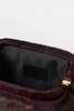 [color: black leopard] Close-up of a handbag's interior opening, showing a black faux-fur trim, a black satin lining, a black leather patch with debossed 'BTB' branding, and a gold zipper pull. The exterior fabric has a dark red and black pattern.