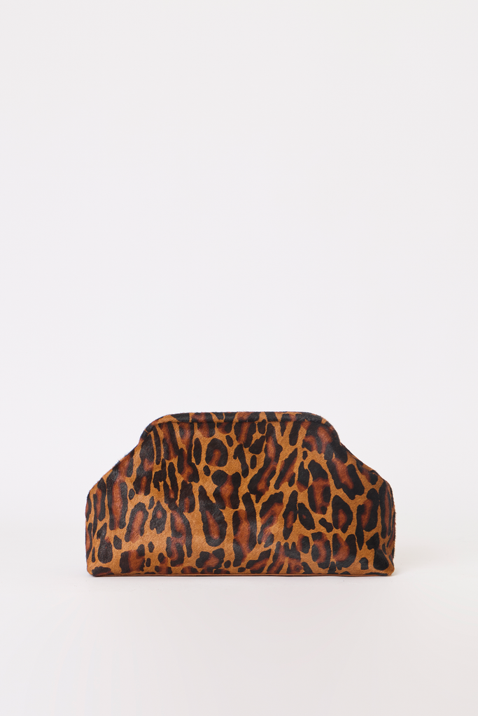 [color:cheetah] A leopard print clutch bag with a structured top handle, featuring a brown and black animal pattern on a tan background, set against a plain white studio backdrop.