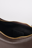 [color: chocolate leather] Close-up of the interior of a brown leather bag, showing a black fabric lining with a black embossed 'BTB' logo patch and a gold-tone zipper.