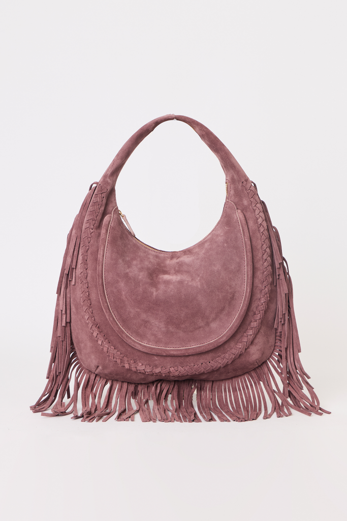 [color: eggplant suede] A dusty rose suede crescent-shaped shoulder bag with long fringe detailing along the bottom and sides, set against a plain light gray background.