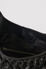 [color:black leather] Close-up of a black leather shoulder bag showing the interior lining, a gold zipper, and a round button detail against a light gray background.