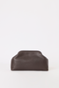 [color: chocolate leather] A dark brown leather cosmetic pouch with a rounded, slouchy shape and a top rim, photographed on a seamless white background.