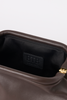 [color: chocolate leather] Close-up of the interior of a brown leather handbag, showing a black fabric lining with a black leather patch embossed with the brand name 'BTB' and a small gold zipper pull visible on the right.