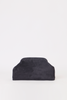 [color: navy suede] A dark charcoal gray suede clutch bag with a structured, rounded top edge, photographed against a seamless white studio background.