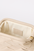 Close-up of the interior of a woven leather clutch or handbag in a warm cream color, showing a beige interior lining with a stitched brand patch that reads 'BTB Los Angeles' and a small gold-tone zipper pull.