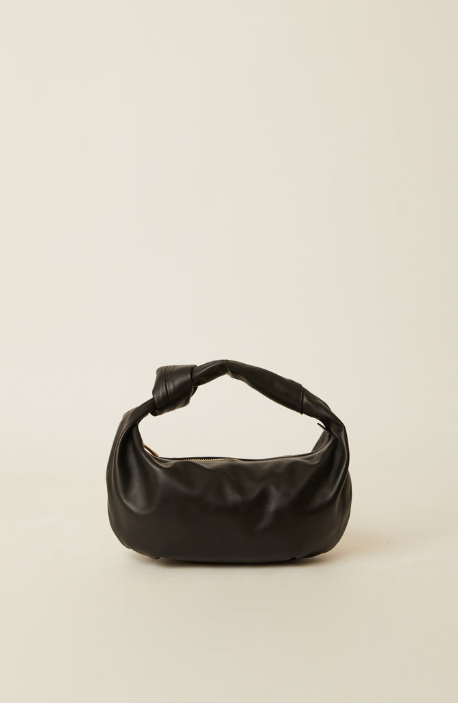 A black leather slouchy shoulder bag with a knotted handle, photographed against a solid off-white background.