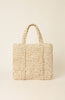 A textured woven tote bag in a natural beige and cream raffia-like material, featuring two top handles and a structured rectangular shape, set against a solid cream background.