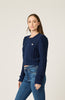 Woman wearing a navy blue knitted sweater and jeans on a light background