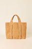 A natural straw tote bag with pearl-beaded handles and vertical pearl-beaded trim details, set against a solid cream background.