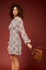Woman wearing a patterned dress holding a brown bag against a red background