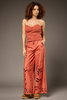 A woman modeling a terracotta-colored two-piece set consisting of a strapless lace-trimmed top and matching wide-leg pants with leaf cutout details, photographed against a solid gray studio background.