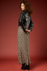 A model is shown from the back wearing a black leather jacket and a long black skirt with a beige and white floral pattern, set against a solid dark red studio background.