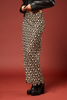 A model is shown from the waist down wearing a black skirt with a beige and brown floral pattern, paired with black platform boots against a solid reddish-brown studio background.